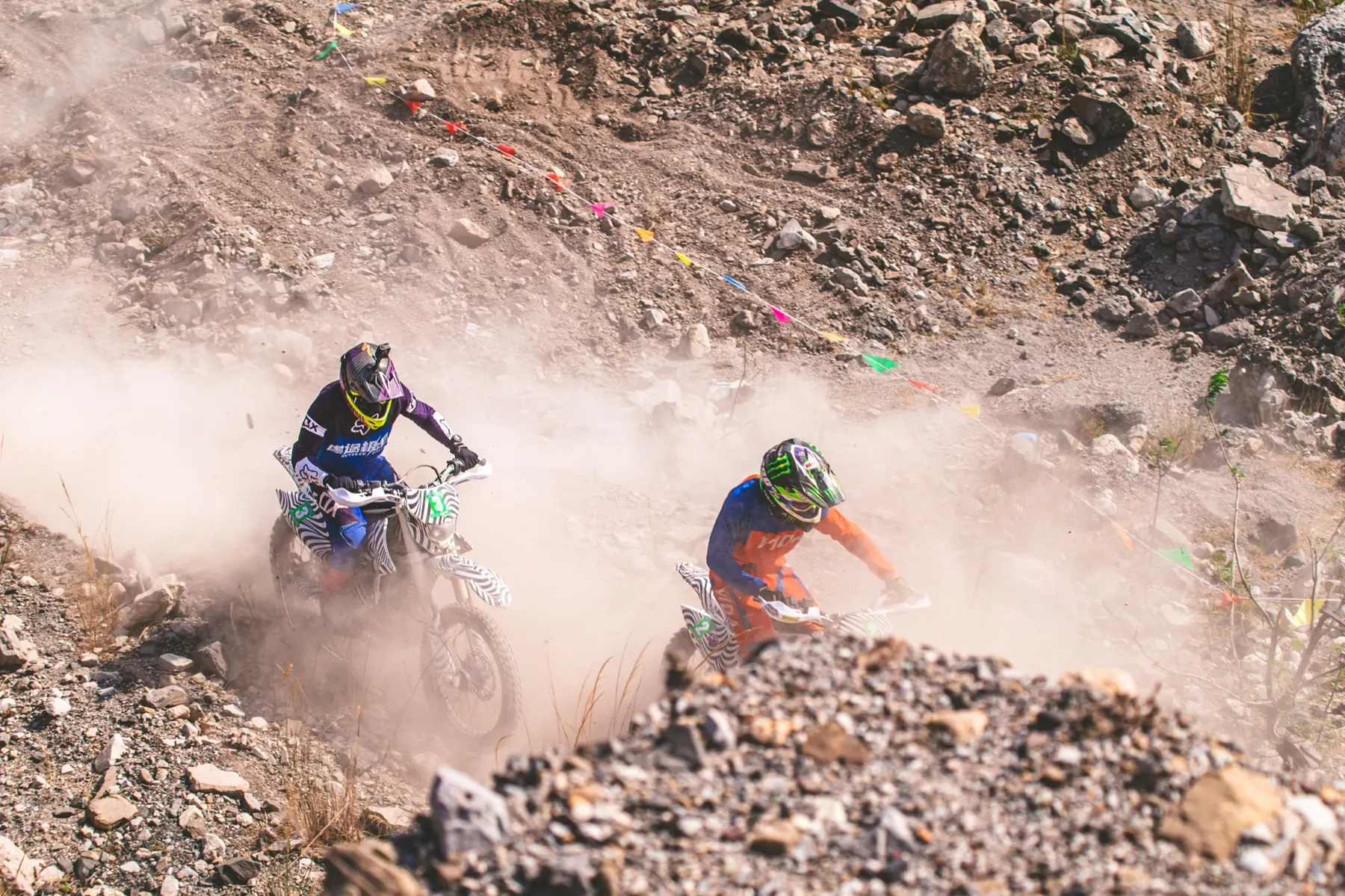 Riders climbing through dust and loose rock